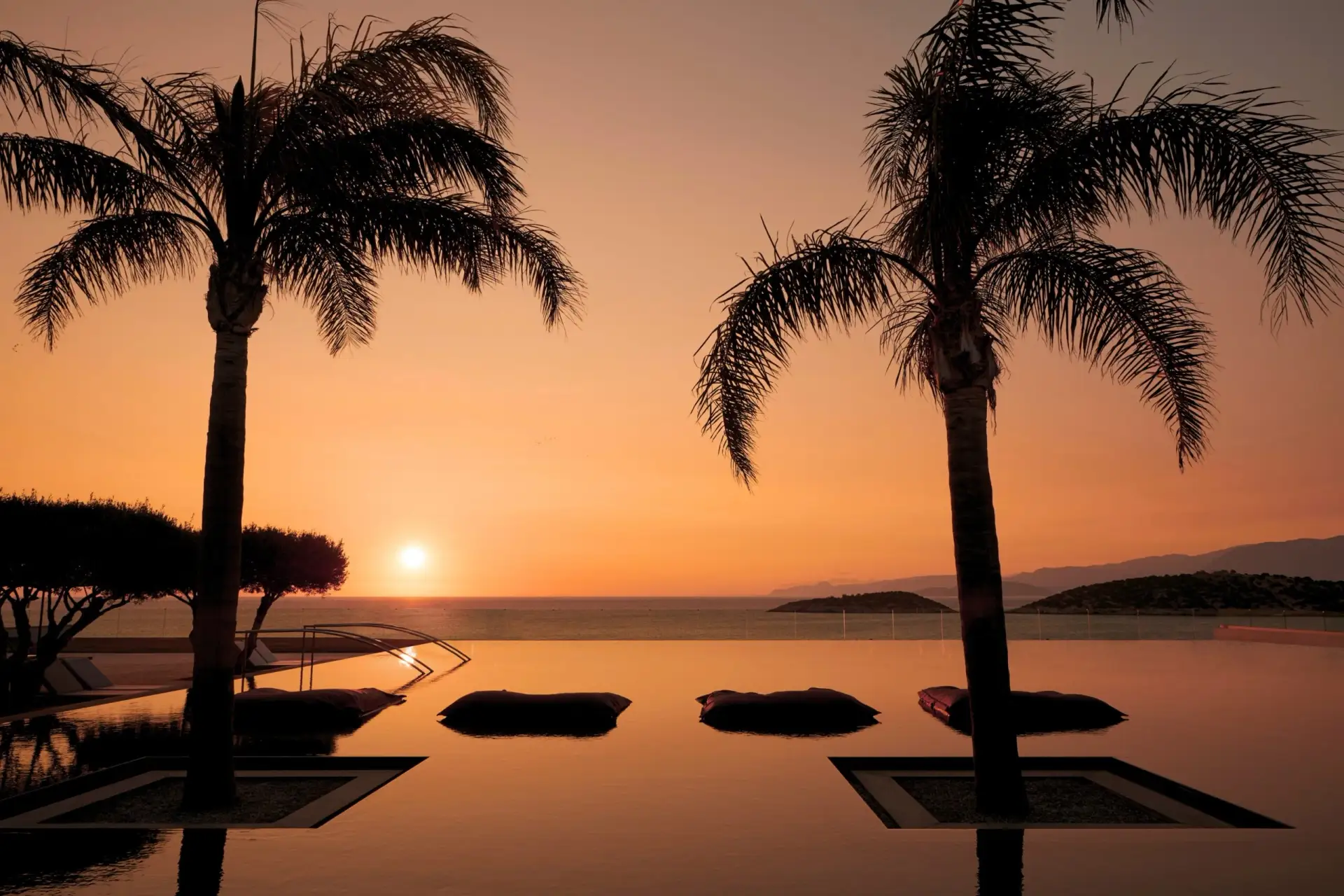 Infinity-Pool bei Sonnenuntergang mit Palmen und Meerblick in einem Luxusresort
