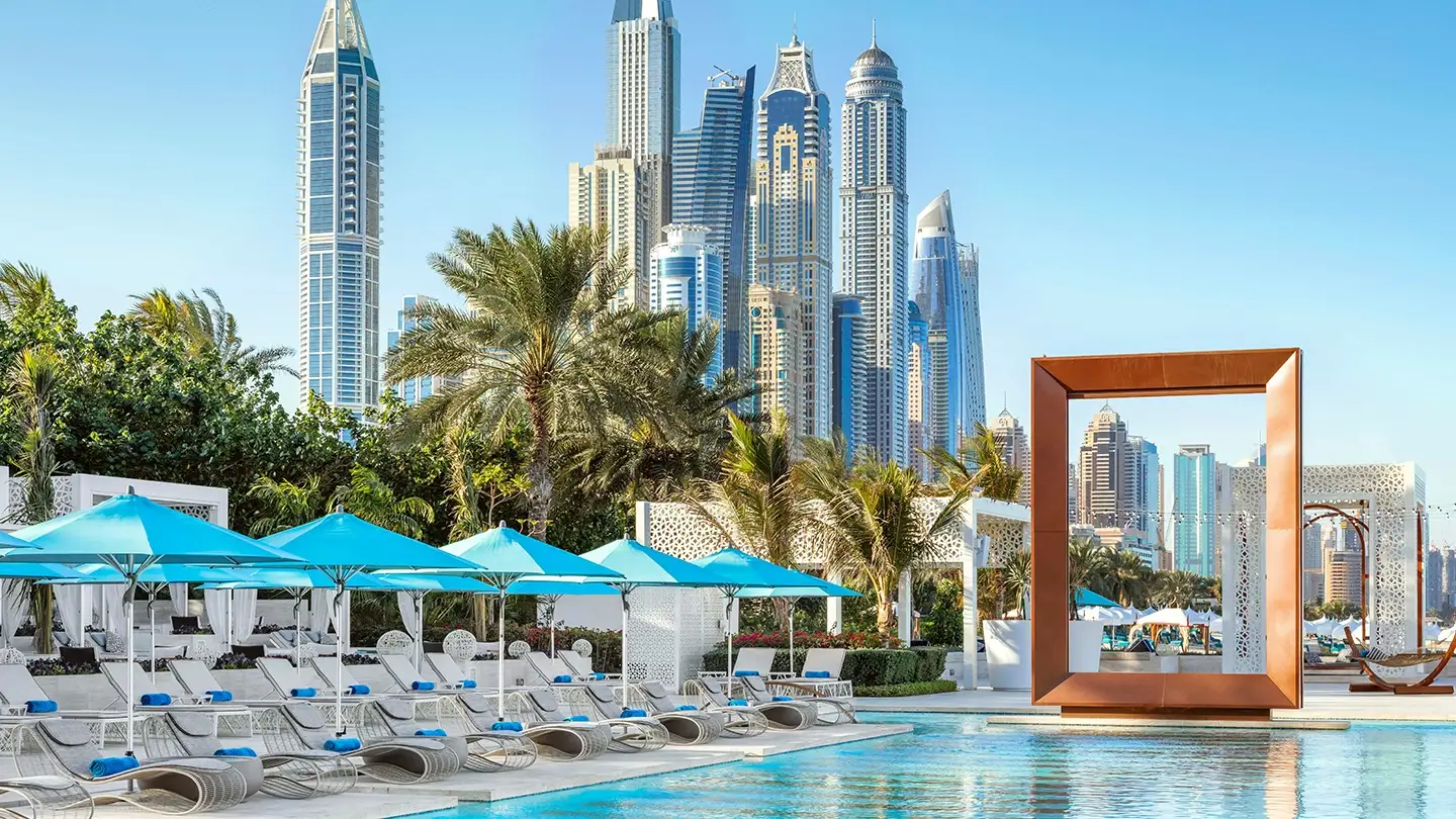 Edler Poolbereich mit Aussicht auf die Skyline der Dubai Marina, Liegestühlen und Palmen in Dubai