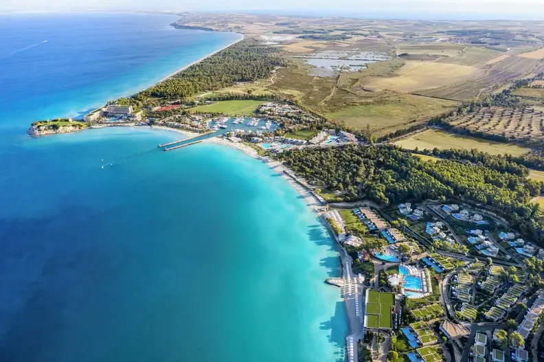 Luftaufnahme des Sani Resorts mit Stränden, Jachthafen und türkisfarbener Küste